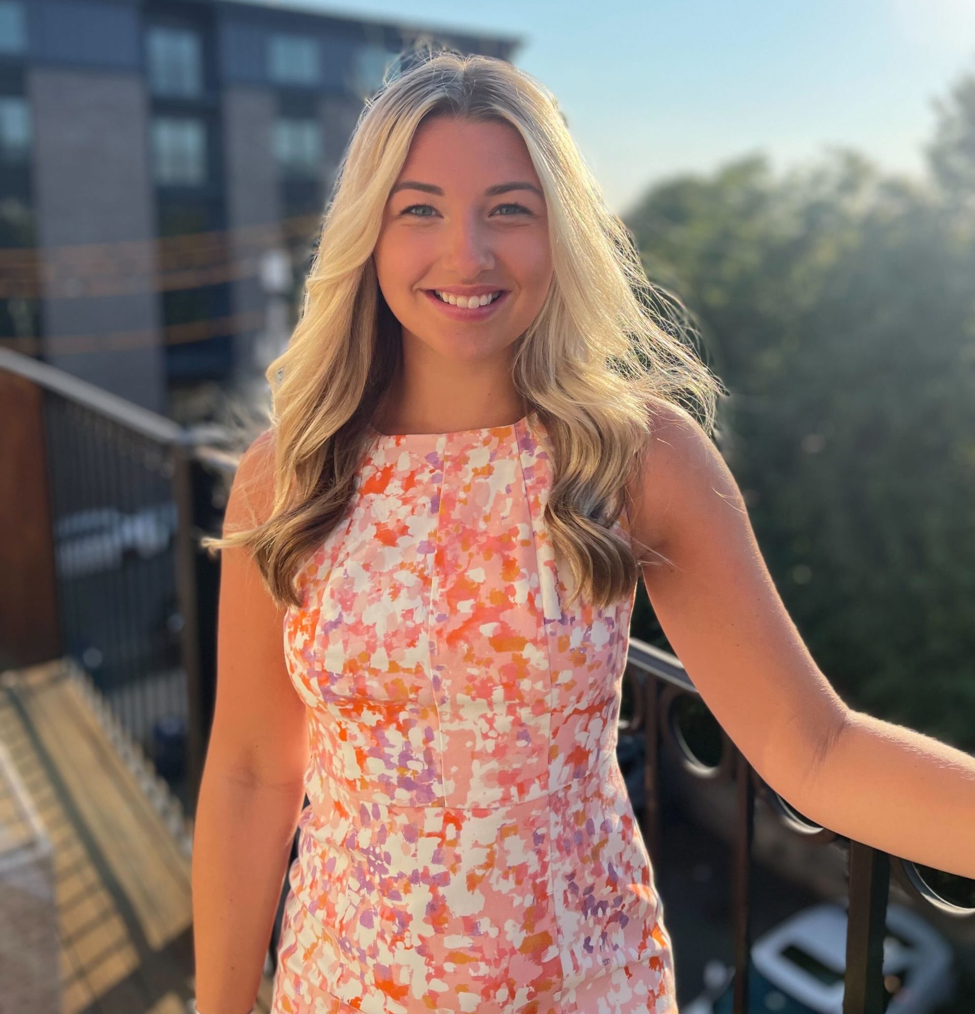 Erin Jones standing on a balcony with the sun glistening behind her